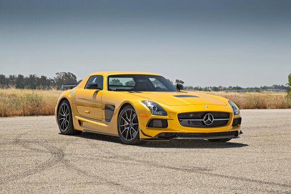 A yellow Mercedes is standing on a platform streaked with wheels