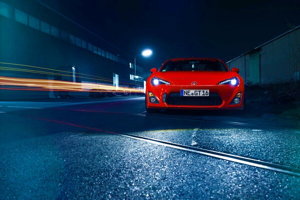 Rotes Auto auf der Straße am Betonzaun