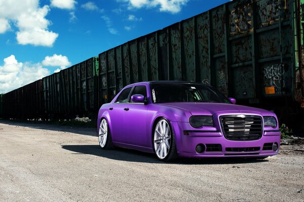 Chrysler 300C sintonizzato viola accanto ai vagoni ferroviari