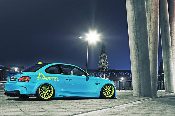 A blue tuned car stands under the lights