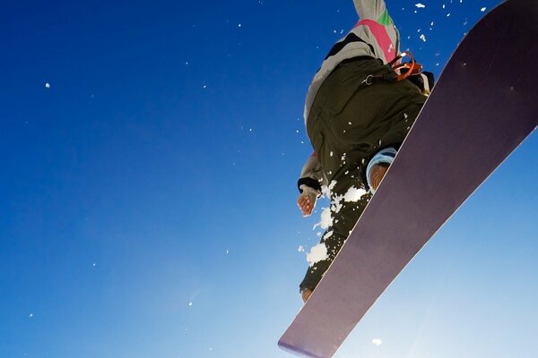 Cielo blu senza nuvole con primo piano dello snowboarder