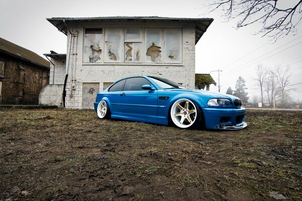 Blue BMW on the background of an abandoned house