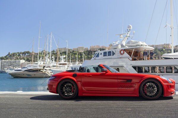 Ein roter Mercedes-Benz am Meer, umgeben von Yachten