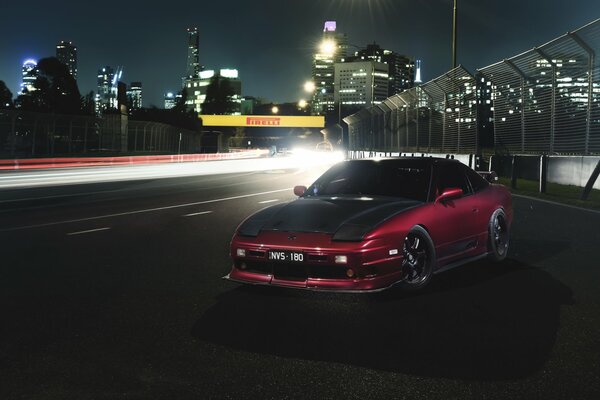 Un nissan 180sx en medio de una ciudad nocturna