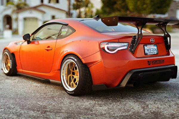 Orange racing car on the background of a cottage