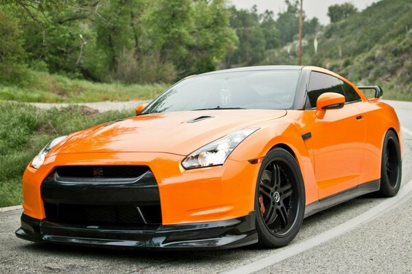 Orange nissan gtr est entré dans un virage serré sur la route