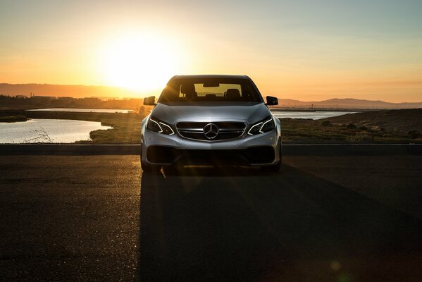 Graues mercedes-benz e63 Auto auf Sonnenuntergang Hintergrund