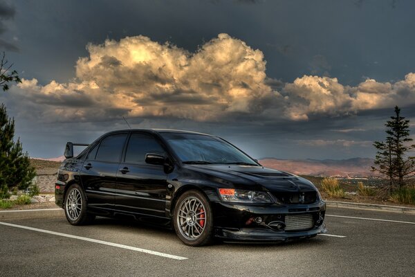 Granatowy mitsubishi evolution na tle burzowego nieba