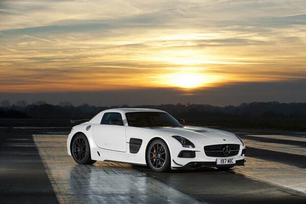 Blanco Mercedes-Benz SLS AMG en el fondo de la puesta de sol