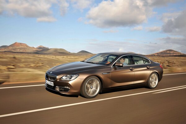 A sporty bmw is driving on a deserted road