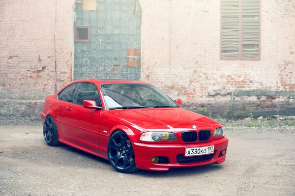 Red BMW on the background of an abandoned building