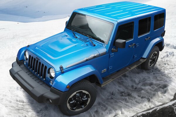 Blue Jeep wrangler in the snowy mountains