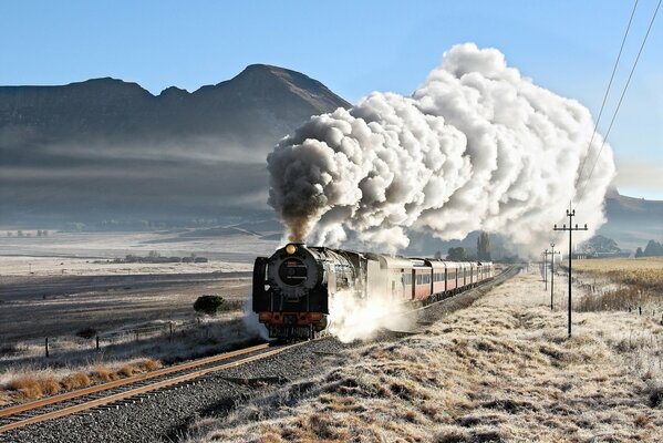 Antigua locomotora de vapor de pasajeros en el fondo de una montaña con niebla