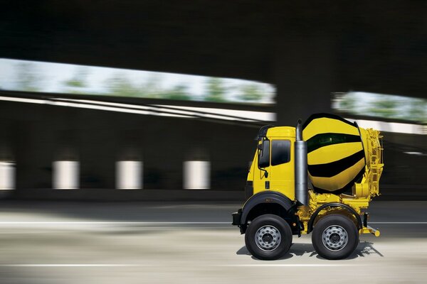 Yellow concrete mixer at speed on the road