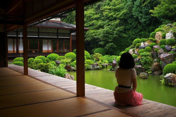 A girl looks at a pond decorated with stones