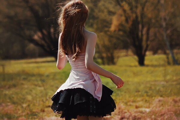 A girl in nature. Brown-haired woman with her back