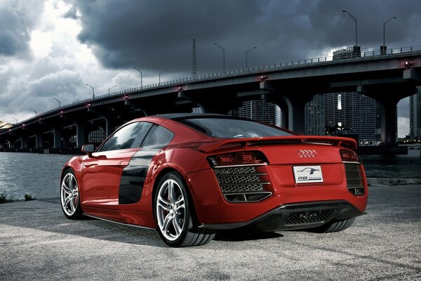 A red Audi is parked near the bridge