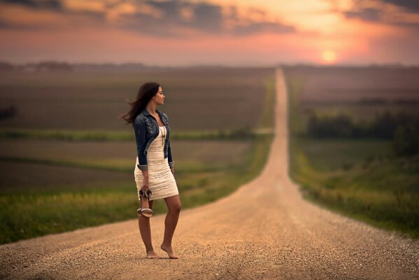 Fille aux pieds nus en attendant debout sur la route