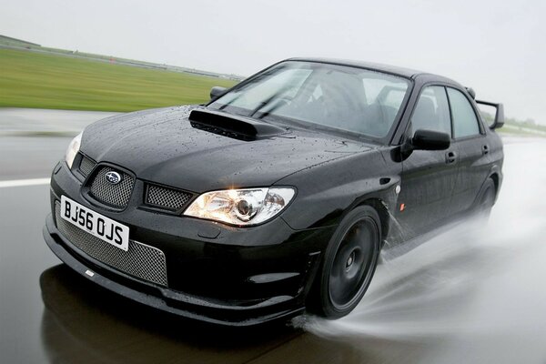 Black subaru on a rainy road