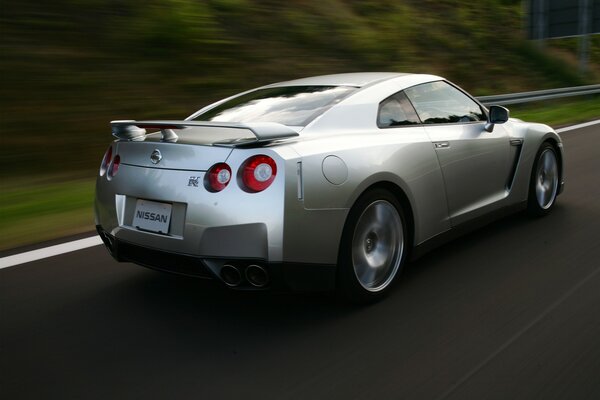 A silver car is driving on the highway