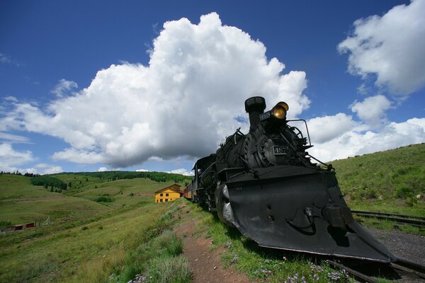 Locomotiva nera su uno sfondo di cielo blu con nuvole