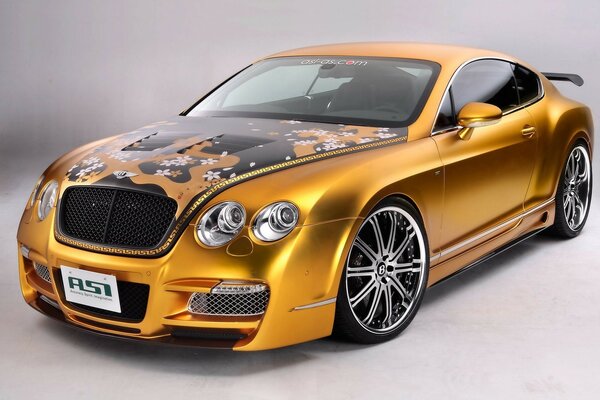 Bentley afinado de color dorado con graffiti en el capó