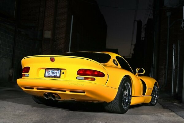 A yellow sports car drives through the night roads