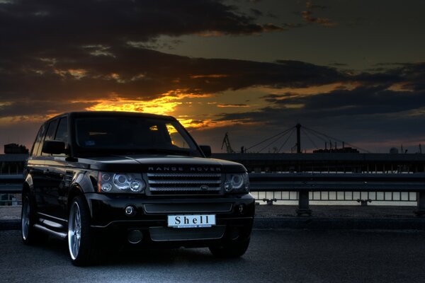 Range rover con puesta de sol y puente