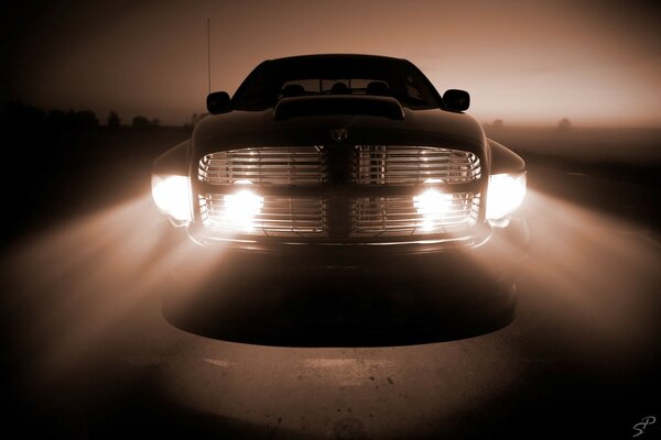 The lights of the front headlights of the car are moving directly towards the viewer