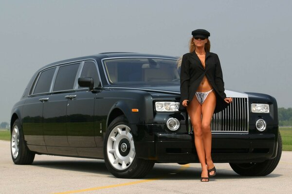 A girl in a jacket with bare legs in front of a car