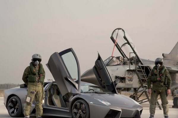 Piloci samolotu w pełnym wyposażeniu obok lamborghini