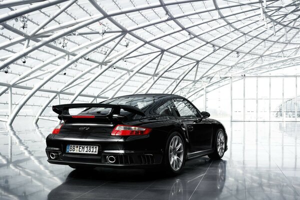 Porsche 911 noire dans un hangar futuriste transparent