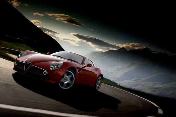 Coche rojo alfa Romeo en la carretera en las montañas