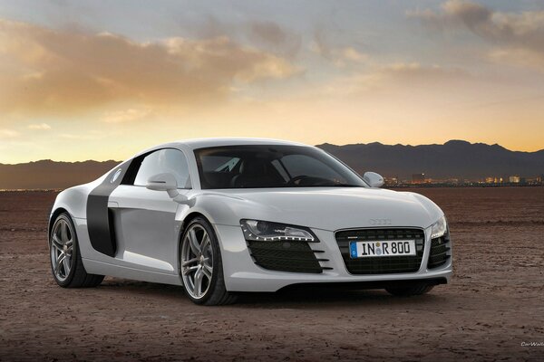 White audi in a field above a beautiful sky