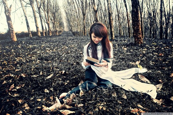 Foto de otoño en el bosque. Chica con un libro