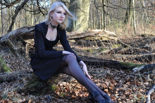 Fille blonde en robe noire sur fond d arbres