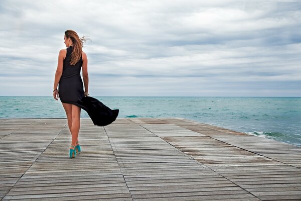 Fille en robe noire près de la mer