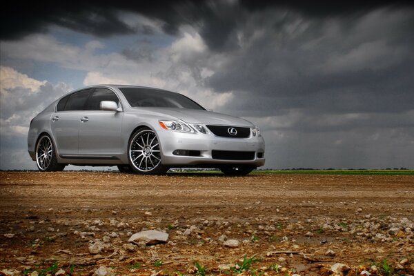 A silver Lexus standing in a rocky area against a gray cloudy sky