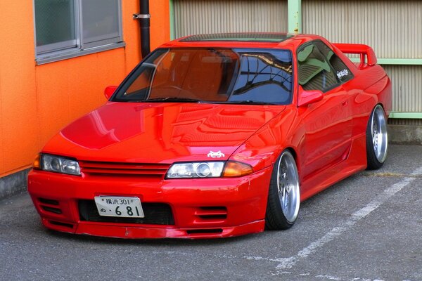 Coche rojo contra la pared naranja