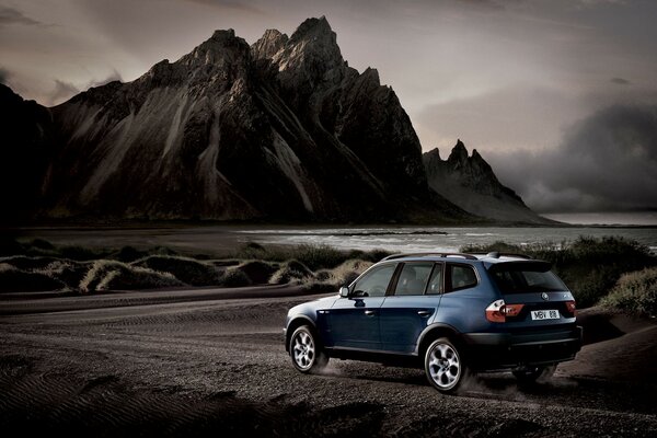 Blauer bmw x3 auf dem Hintergrund von Bergen und Wasser