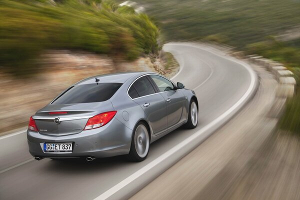 Un coche gris de la marca Opel corre por la carretera