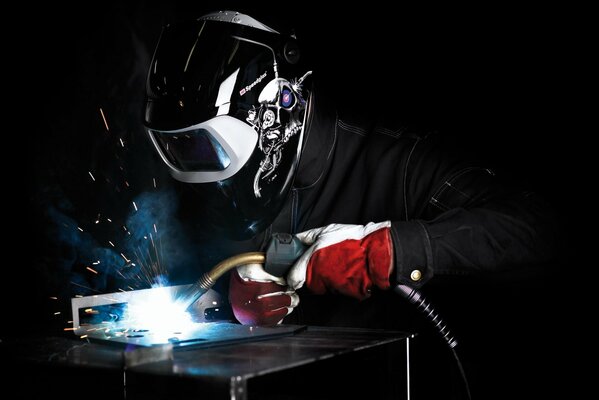 A male electric welder in a mask cooks a part sparks fly