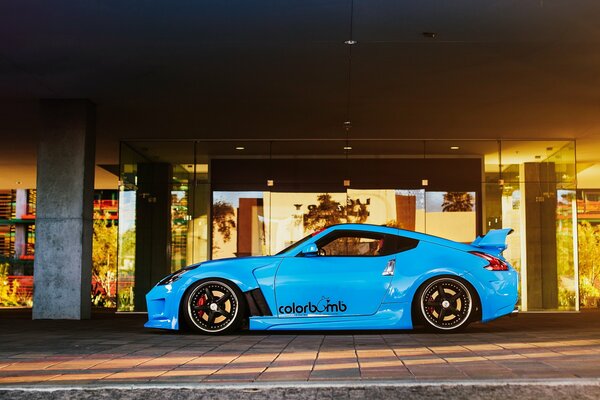 El nissan 370Z es un coche tuneado de color azul brillante sobre el fondo de la arquitectura moderna