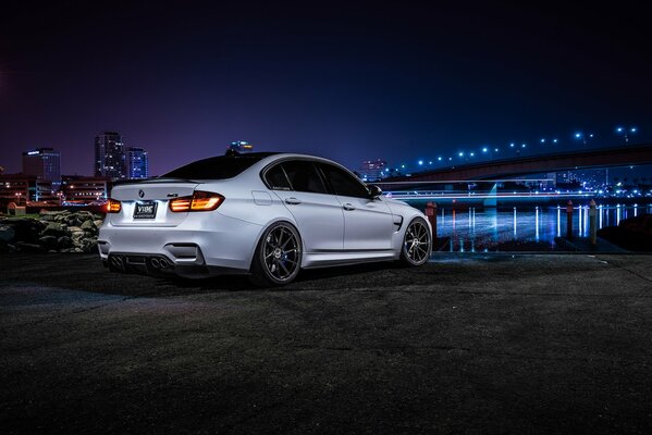 White bmw m3 f80 on the background of a bridge and a river