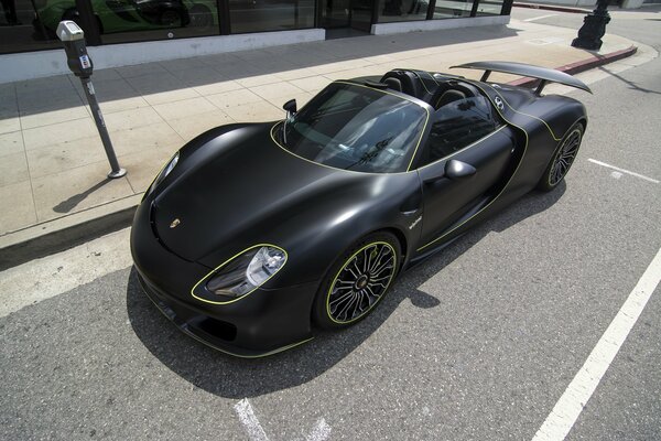 Una Porsche 918 spyder nera su una strada soleggiata