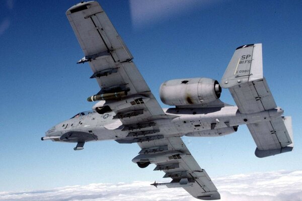 A military plane is piloting above the clouds