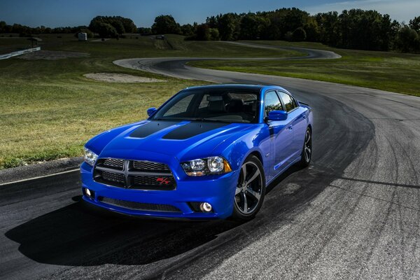 Blue Dodge flying on the track on the background of the field 