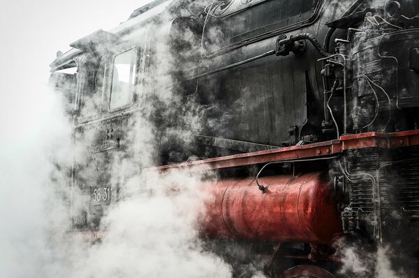 A steam locomotive with a red tank in smoke