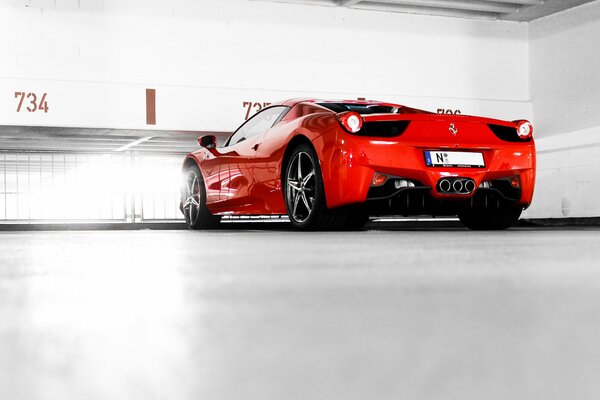 Une ferrari 458 Italia rouge se tient dans une salle blanche