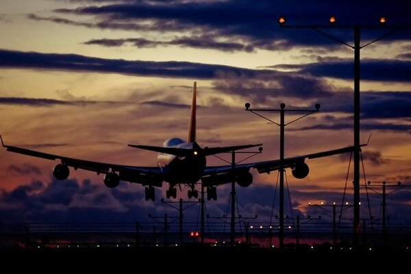 Das Flugzeug sitzt auf einem Streifen vor dem Hintergrund eines schönen Sonnenuntergangs